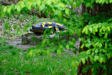 Large plastic salamander figurine on a concrete pedestal.