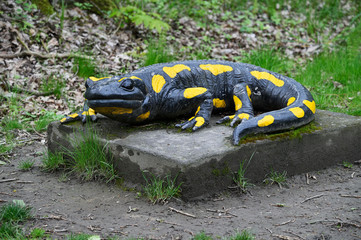 Large plastic salamander figurine on a concrete pedestal.