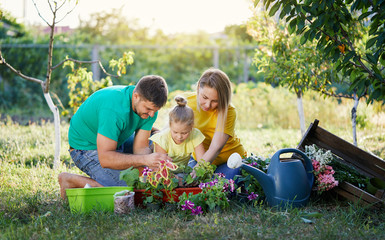 Happy family gardening together and taking care of nature. Plant sprouts and fertilize the ground. Hugging and having fun. Show dirty hands to the camera