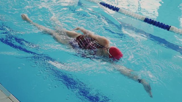 Top view of professional young woman while she swim backstroke style. She prepare for great competition of popular swimmers. Physical effort for health. Super slow motion shot