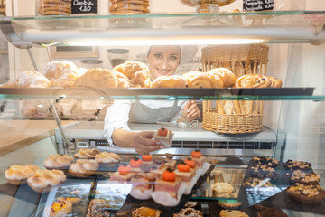 Confectioner shot through glass display in her shop