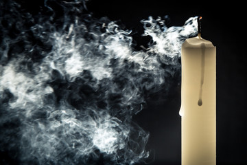 Smoke and extinct candle on a black background