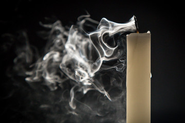 Smoke and extinct candle on a black background