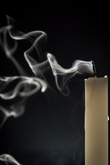 Smoke and extinct candle on a black background