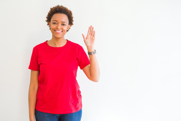Young beautiful african american woman over white background Waiving saying hello happy and smiling, friendly welcome gesture