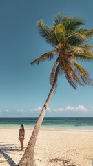 Palm trees and the girl on the white beach in Tulum caribbean, Mexico