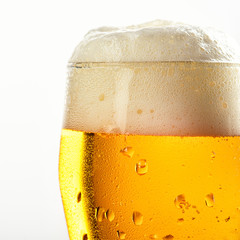 misted beer glass with foam closeup on white background