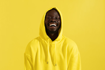 Portrait of happy black man in yellow hoodie on color background