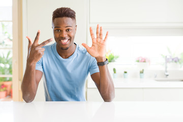 Handsome african american man wearing casual t-shirt at home showing and pointing up with fingers number eight while smiling confident and happy.