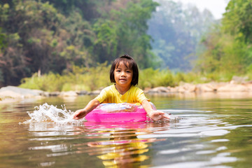 Fototapeta premium Little Asian girl with pool ring floating in river