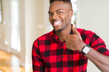 Handsome african american man doing happy thumbs up gesture with hand. Approving expression looking at the camera with showing success.