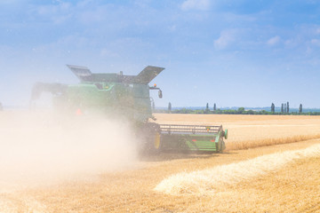 The machine for harvesting grain crops - combine harvester in action on rye field at sunny summer...