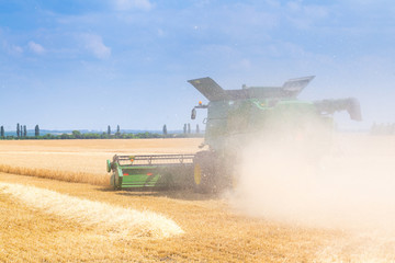 The machine for harvesting grain crops - combine harvester in action on rye field at sunny summer...