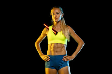 Professional female relay racer training isolated on black studio background in neon light. Woman in sportsuit practicing in running. Healthy lifestyle, sport, workout, motion, action concept.