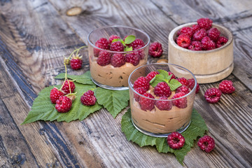 fresh raspberry with chocolate mousse in glass glasses on wooden background