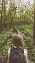 A woman with a backpack in the forest looks at the road ahead