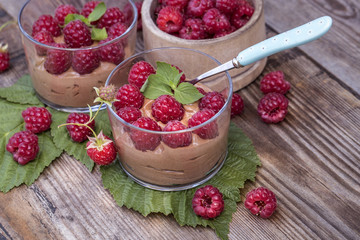 fresh raspberry with chocolate mousse in glass glasses on wooden background