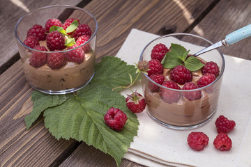 fresh raspberry with chocolate mousse in glass glasses on wooden background