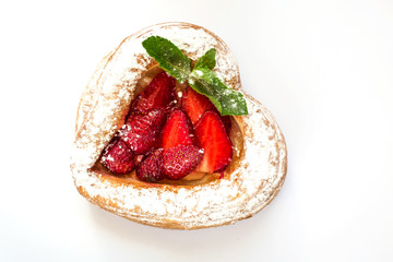 Strawberry cake in the form of a heart from puff pastry decorated with powdered sugar and mint leaves on a white background. Isolate