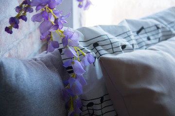 Purple artificial flowers on the windowsill with pillows.