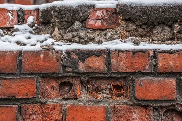 Destroyed brick wall in the street under the snow
