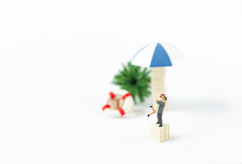 Miniature couple on wooden dice over blurred summer item set background, summer and holiday concept, couple happy on holiday