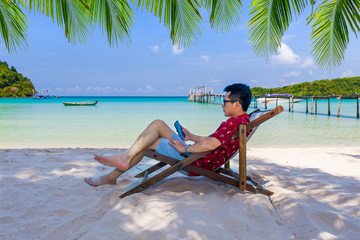 Obraz premium Man sitting on the beach at tropical sea.