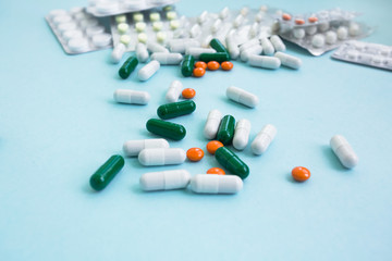 white, orange and green pill capsules falling on a blue background copy space