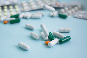 white, orange and green pill capsules falling on a blue background copy space