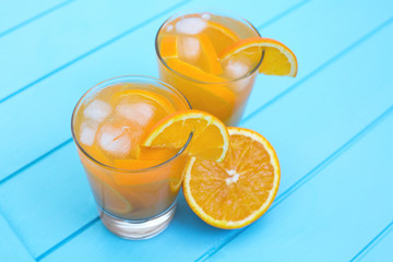 Alcoholic and non-alcoholic citrus drink with orange and lemon in glasses on a light blue wooden background