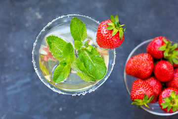 alcoholic cocktail with liqueur in a high glass with olives, mint and strawberries