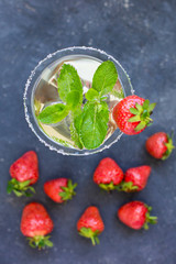 alcoholic cocktail with liqueur in a high glass with olives, mint and strawberries