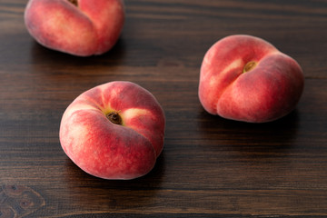 Naklejka na ściany i meble Fresh organic saturn peaches on a dark wooden table