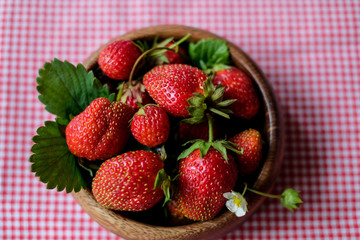 Bowl with red strawberries at dark wooden background,closeup