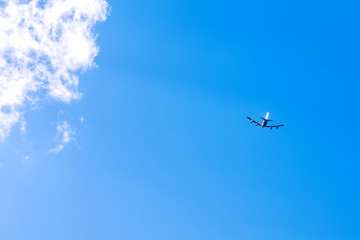 the silhouette of an airplane that flies against the blue sky and clouds