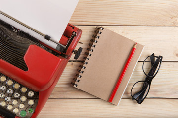Writer or journalist workplace - vintage red typewriter on the wooden desk