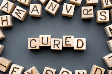 word cured composed of wooden cubes with letters, scattered around the cubes random letters, top...