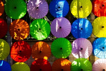 Fototapeta na wymiar traditional colorful paper umbrellas hanging in a row on wall in the evening sun in Chiang Mai, Thailand