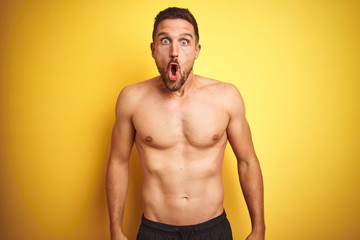 Fototapeta premium Young handsome shirtless man over isolated yellow background afraid and shocked with surprise expression, fear and excited face.