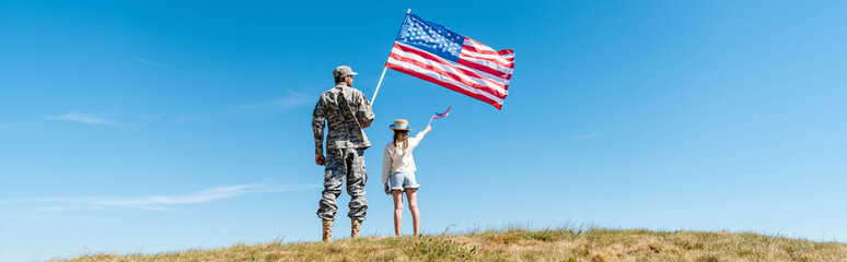 Panoramic shot of kid and military father holding American flags - obrazy, fototapety, plakaty