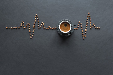 A cardiogram of coffee beans and a cup of coffee on a black background