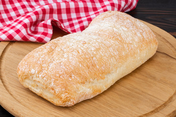 Loaf of ciabatta bread on a cutting board on the dark wooden table