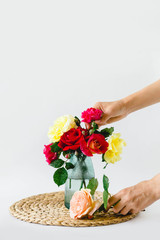 Stunning composition of colorful roses in a vase on a wicker napkin