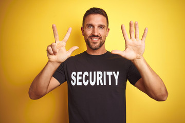 Young safeguard man wearing security uniform over yellow isolated background showing and pointing...