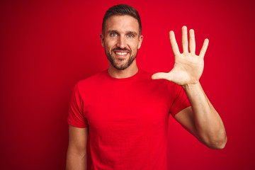 Young handsome man wearing casual t-shirt over red isolated background showing and pointing up with fingers number five while smiling confident and happy.