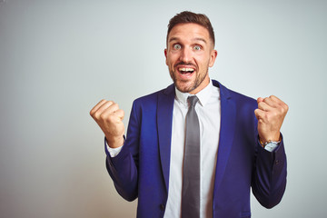 Young handsome business man over white isolated background celebrating surprised and amazed for success with arms raised and open eyes. Winner concept.