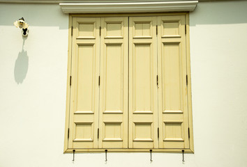 Vintage wooden windows and classic wall lamp with shadow on white shadow on cement wall background.