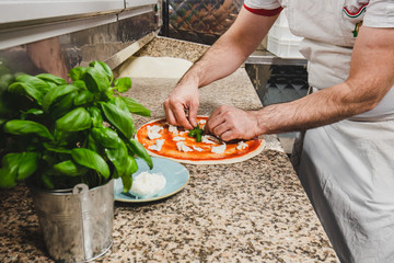 Preparing a pizza margherita in a professional kitchen