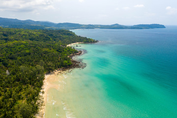 Aerial top view of ocean waves, beach and rocky coastline and beautiful forest. Beautiful nature background.