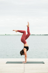 Fototapeta na wymiar Asian young girl doing yoga outdoors on the pier by the lake.